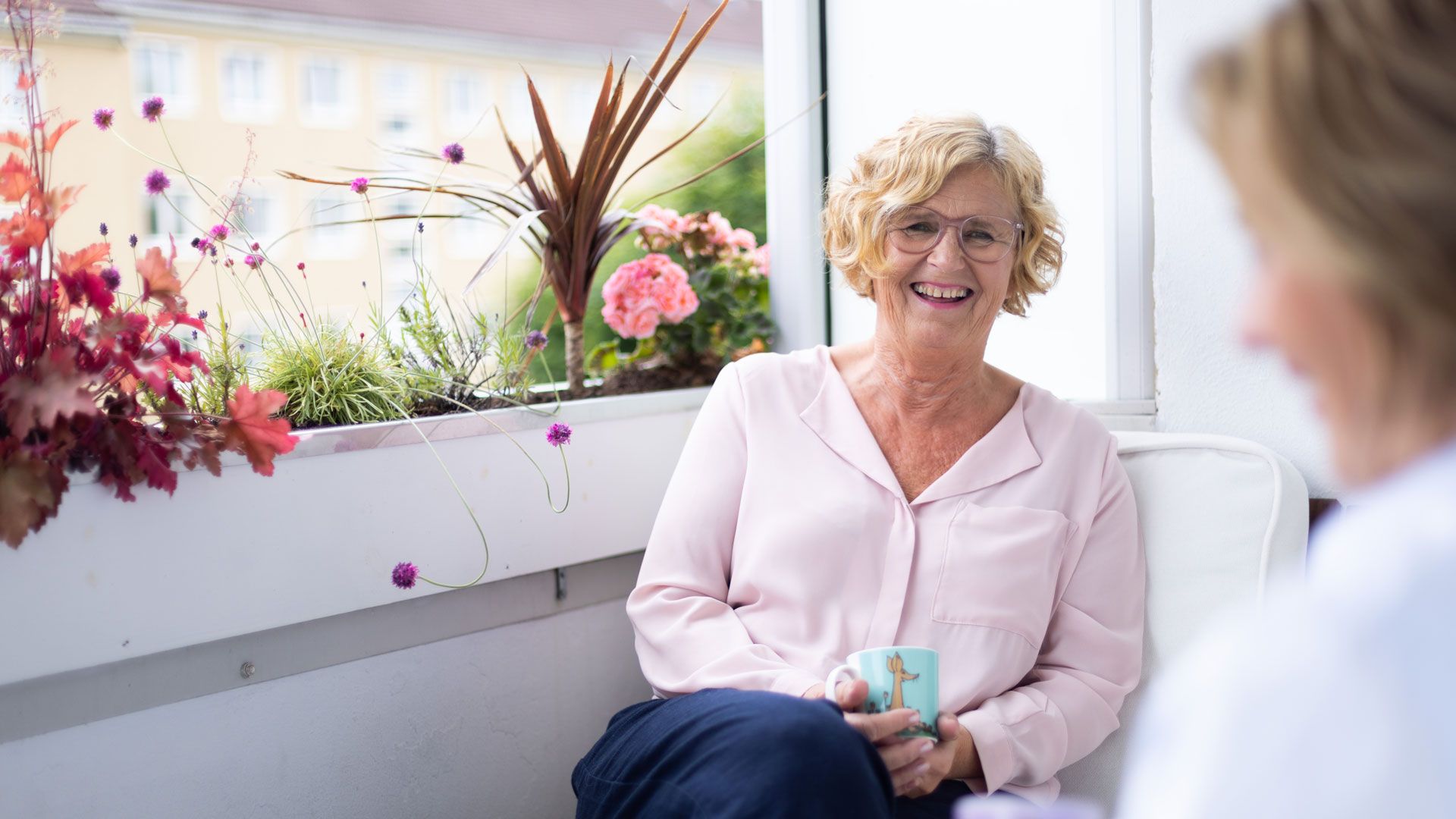 Dame drikker kaffe på balkong