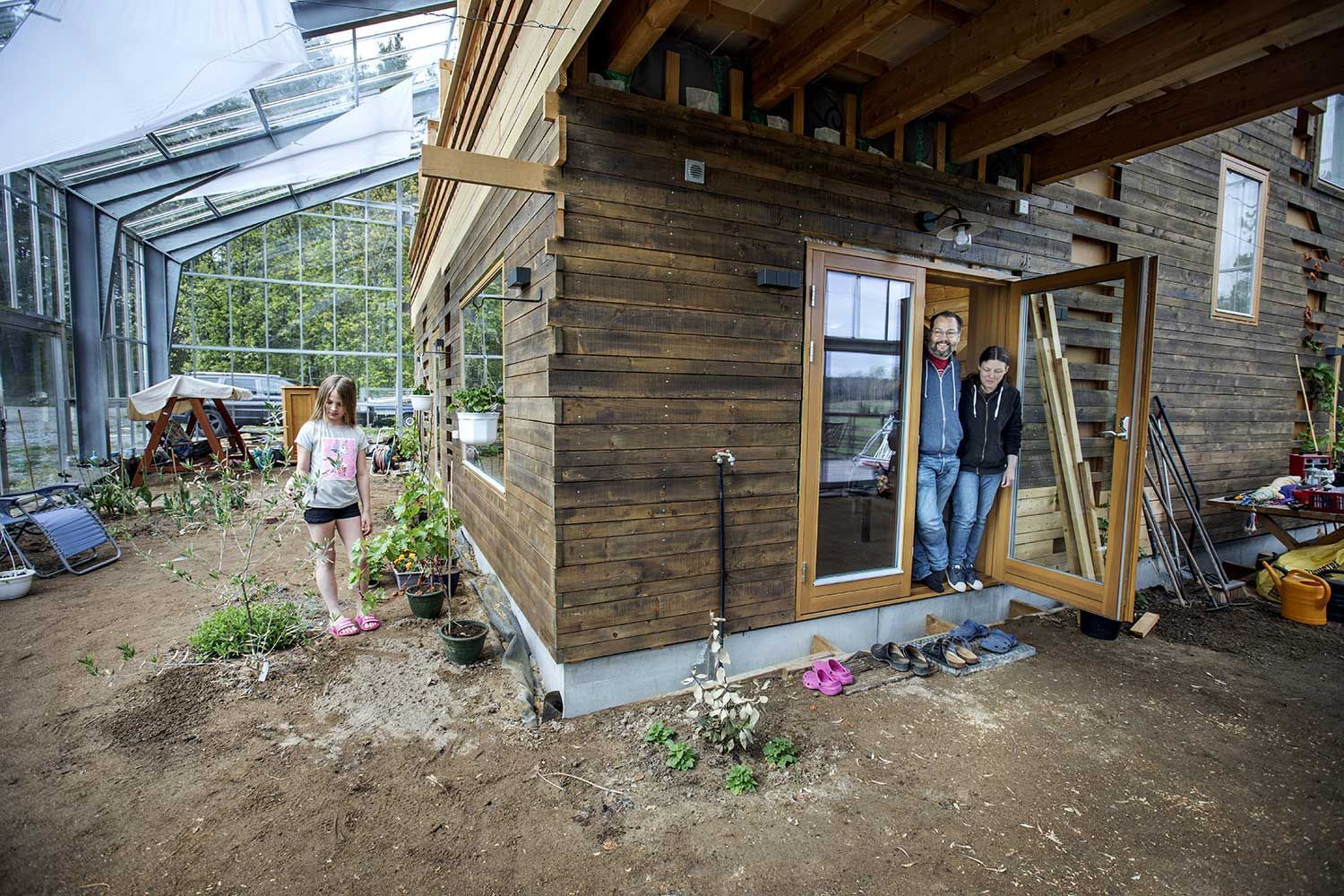 Saga, Björn og Linda Wallentinus i huset sitt - som er bygd inni et drivhus.