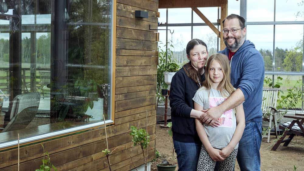 Familie på mor, far og datter utenfor naturhuset sitt