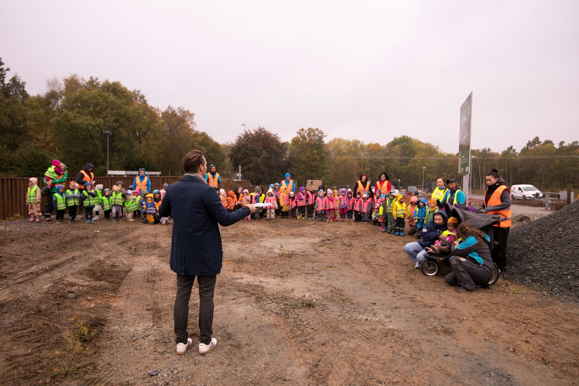 Bates prosjektleder holder tale foran besøkende naboer