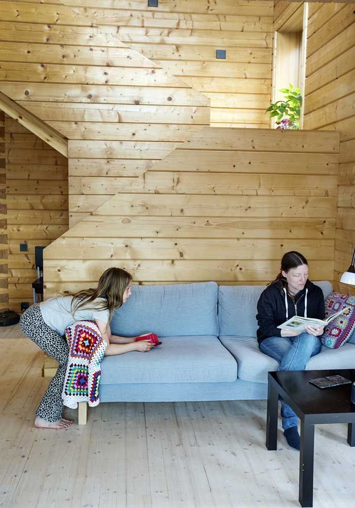 Mor leser bok i sofaen og datter lener seg på sofaen