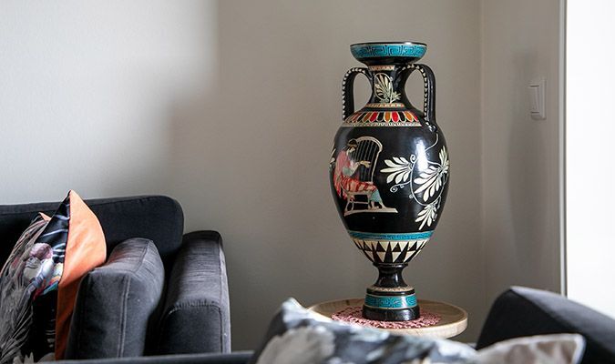 Høy vase med håndmalt motiv på sidebord ved sofa