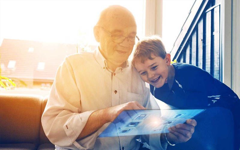 Bestefar og barnebarn sitter med skjermbrett